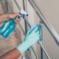 A man cleaning staircase handrail in gloves . coronavirus